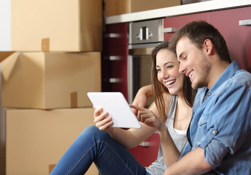 Couple moving home and buying online with a tablet sitting on the floor in the kitchen